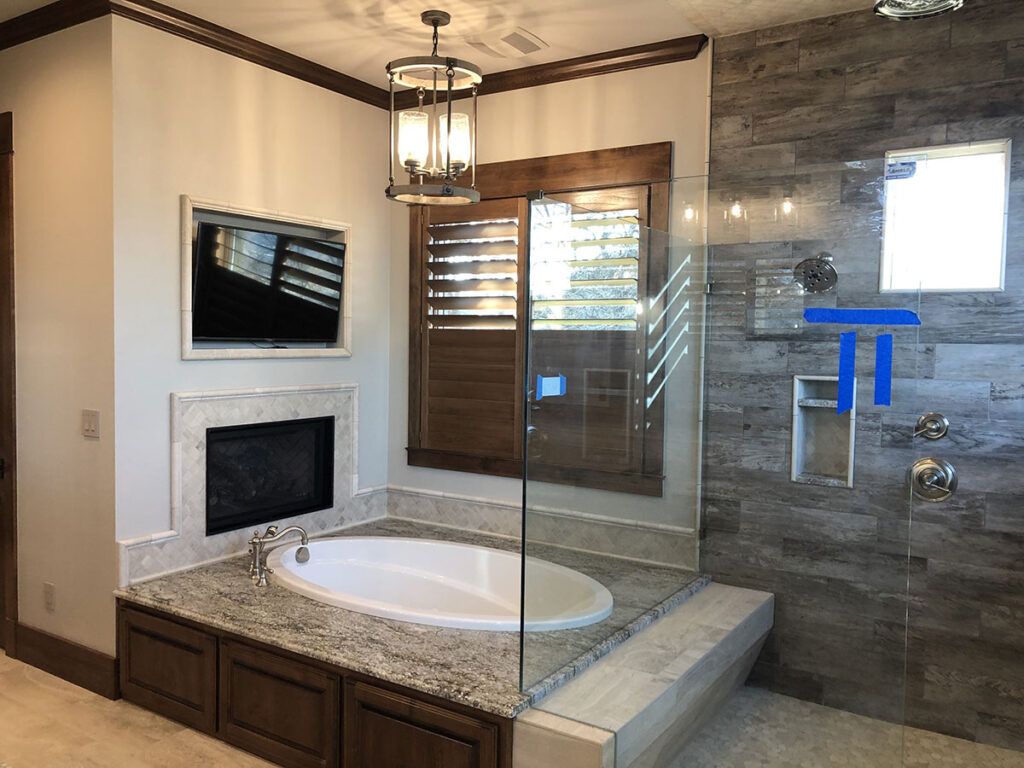Bathroom with sunken tub, glass shower, fireplace and TV