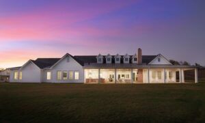 Sunset view of exterior of new custom home with patio